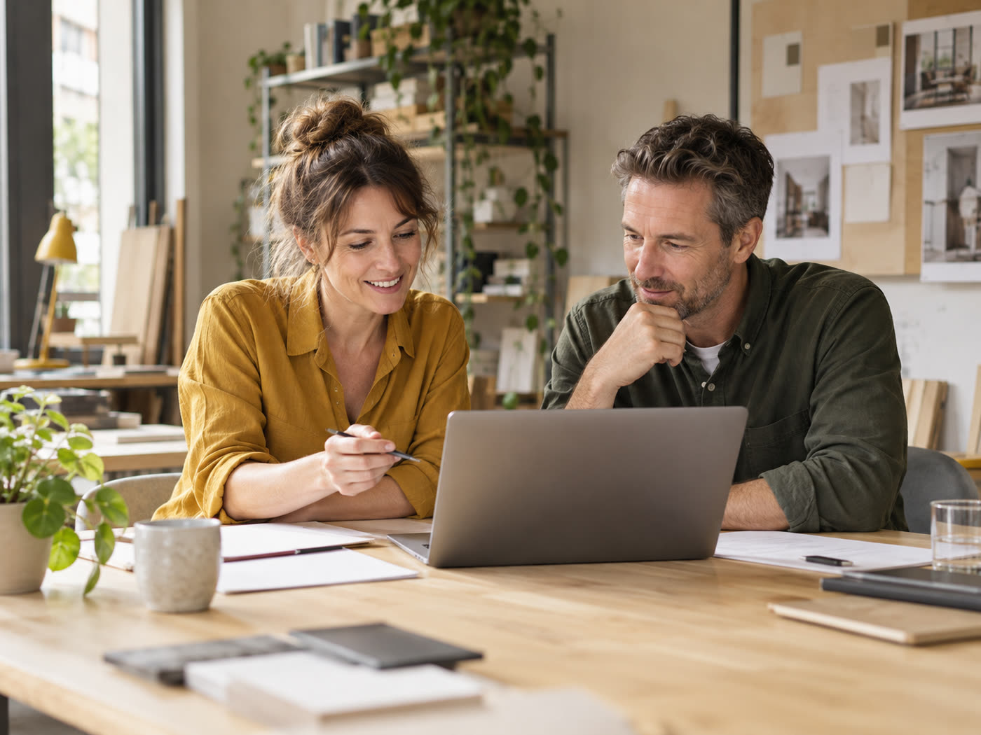 Zwei Selbstständige besprechen sich am Laptop in ihrem Atelier